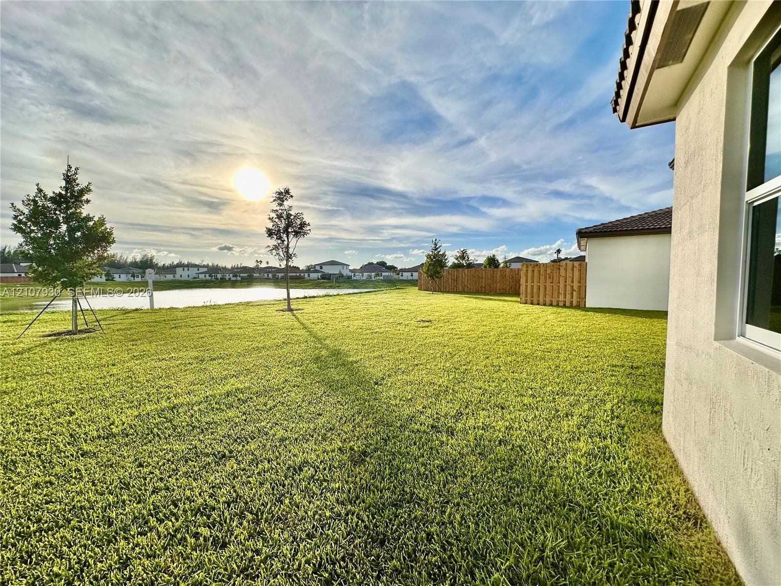 Backyard featuring a manicured lawn, water frontage, and wood privacy fencing
