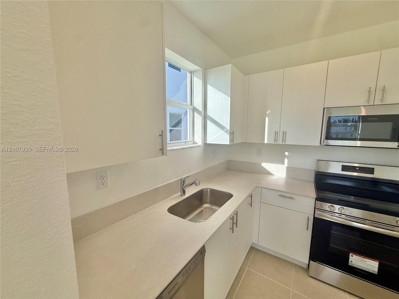 Kitchen featuring white cabinetry, solid surface countertops, stainless steel undermount sink, and stainless steel appliances