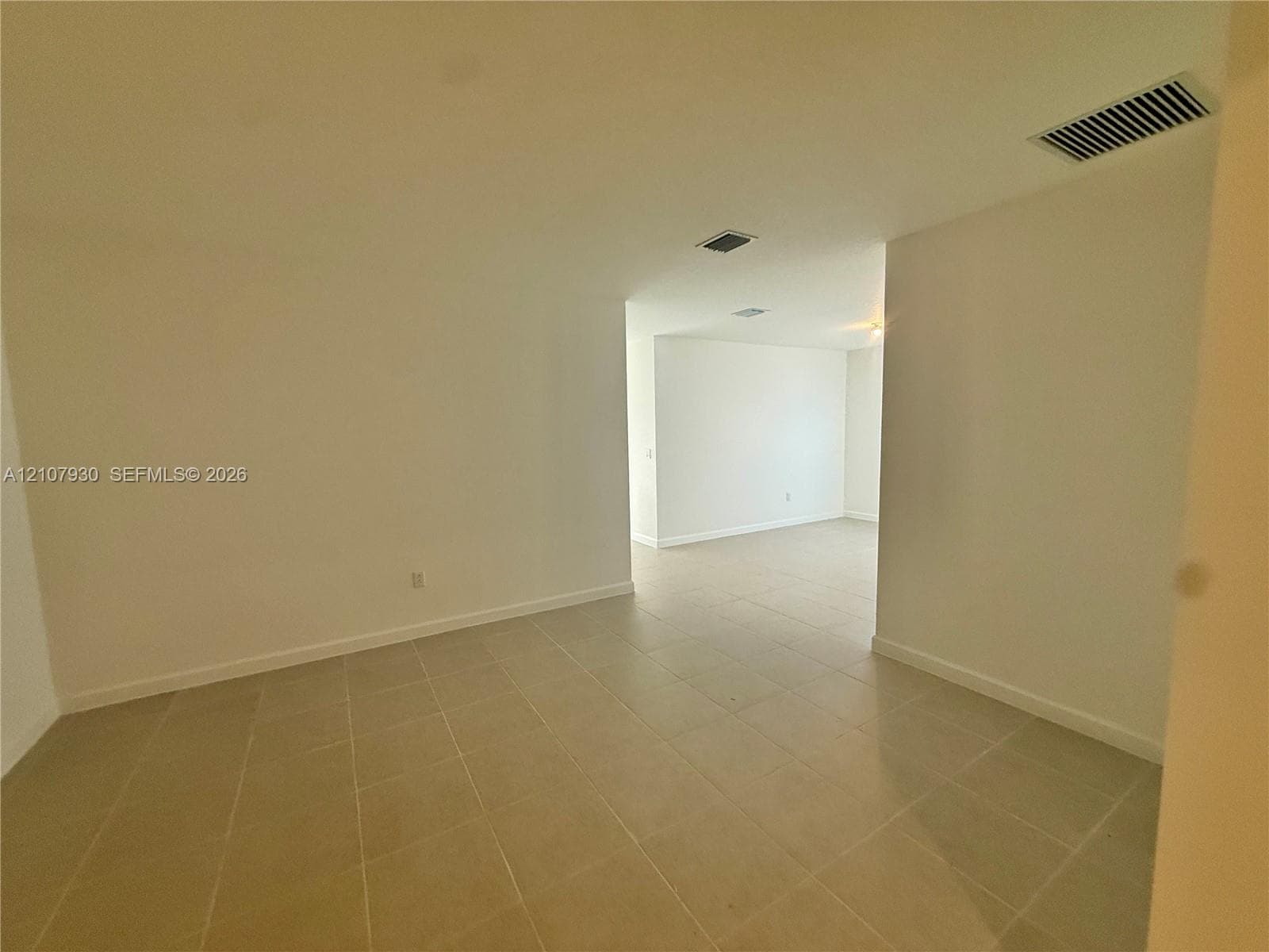 Neutral-toned ceramic tile flooring throughout the interior, complemented by smooth walls and high ceilings