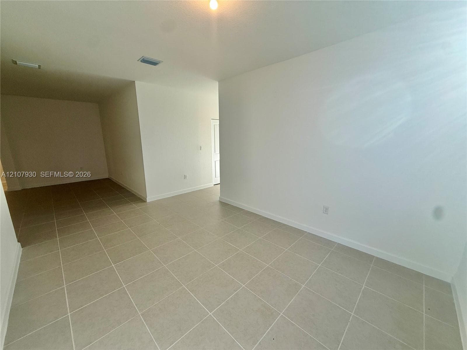 Interior space featuring neutral wall-to-wall tile flooring and crisp white walls
