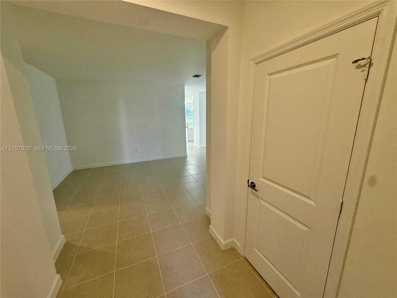 Interior entry featuring large-format ceramic tile flooring, neutral wall finishes, and a single-panel interior door with brushed metal hardware