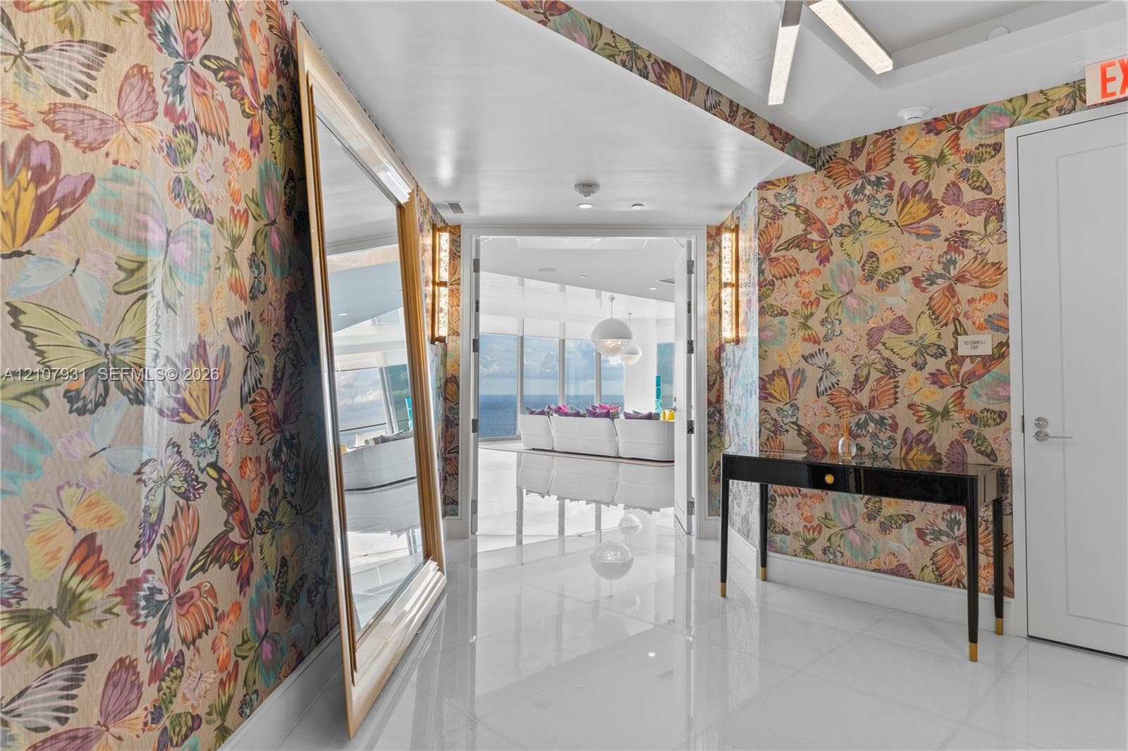Entryway featuring large-scale butterfly pattern wallcoverings, high-gloss tile flooring, integrated linear lighting, and wall-mounted sconces