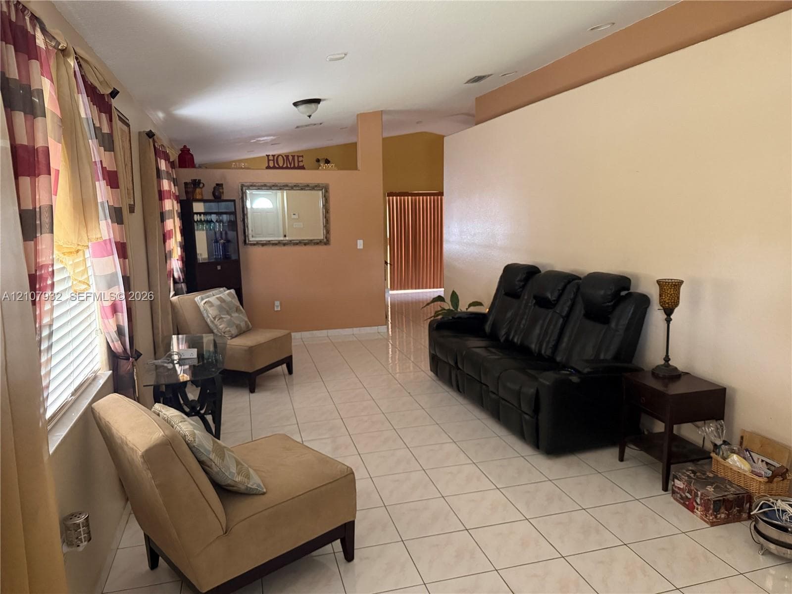Open-concept interior featuring light-toned tile flooring, vaulted ceilings, and recessed lighting