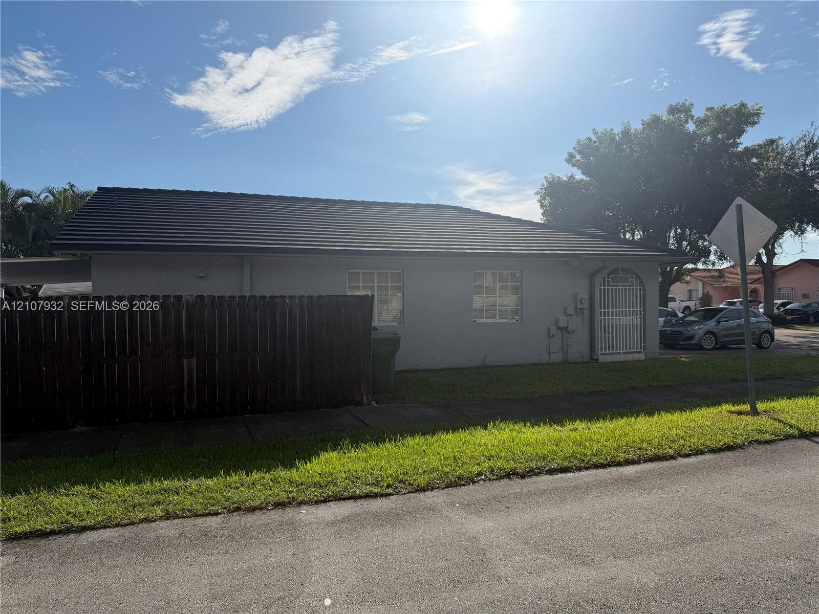 Single-story exterior featuring a concrete tile roof, stucco siding, and a white metal security door