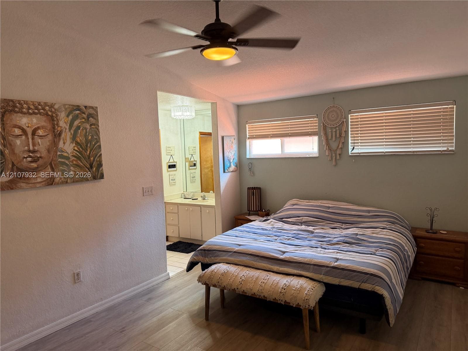 Wood-finish flooring, ceiling fan with integrated lighting, dual horizontal windows with fitted blinds, and built-in vanity cabinet with countertop sink