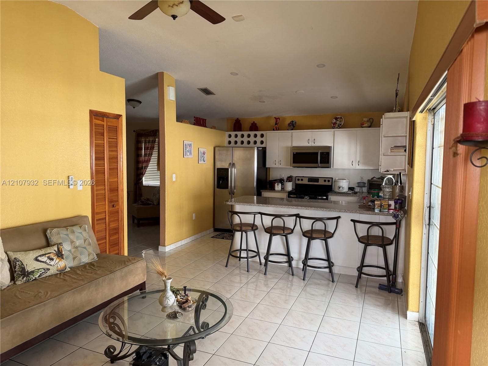 Kitchen featuring white cabinetry, stone-finish countertops, stainless steel appliances, and tile flooring