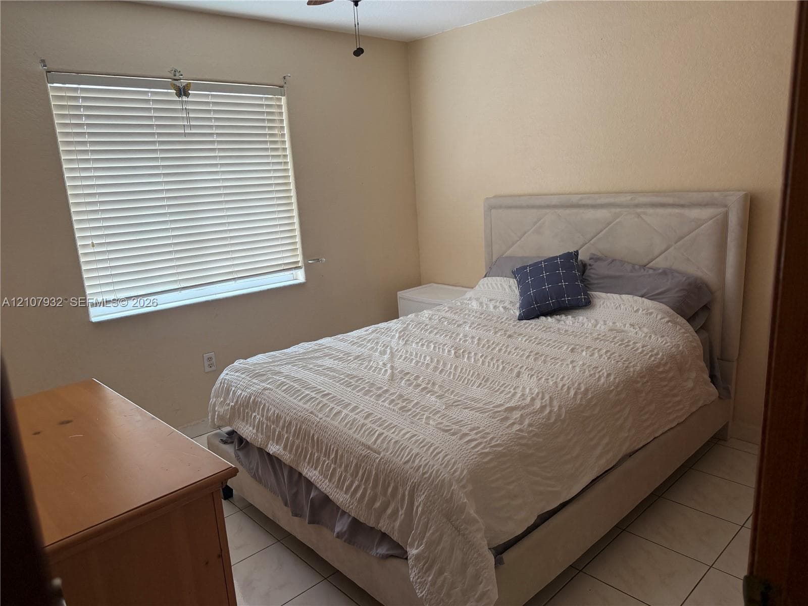Light-toned ceramic tile flooring, neutral wall paint, and window fitted with horizontal blinds