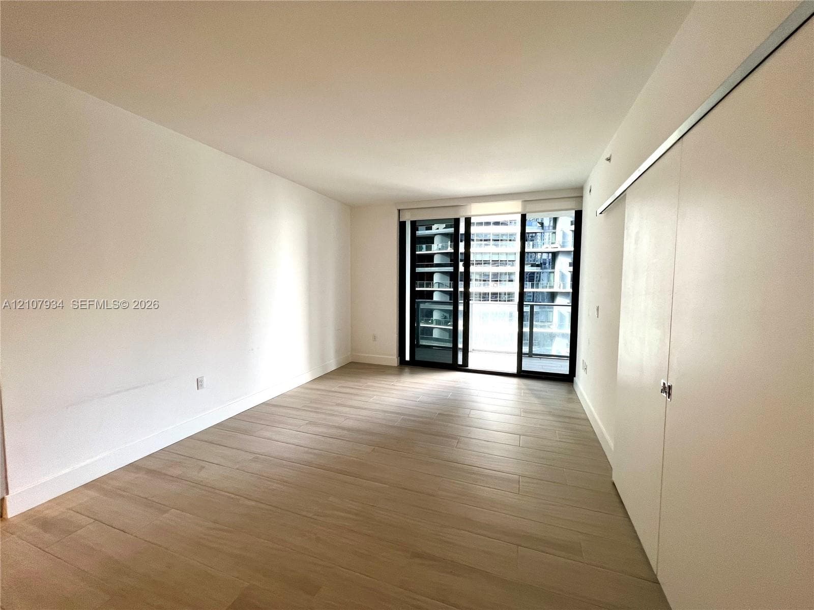 Open interior space with wood-finish flooring, floor-to-ceiling glass sliding doors, and built-in sliding closet doors