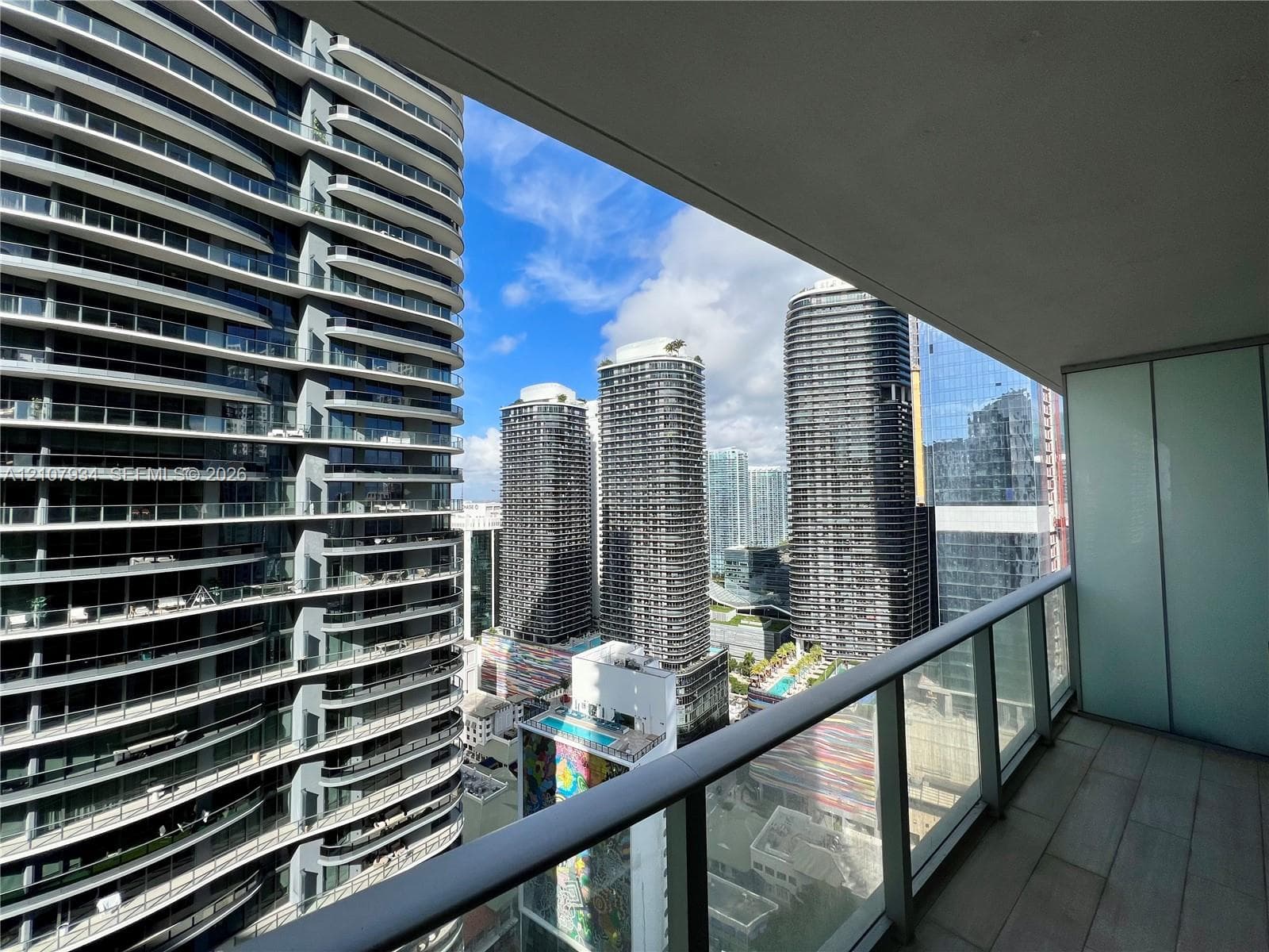 Private balcony featuring a glass-panel railing and large-format tile flooring