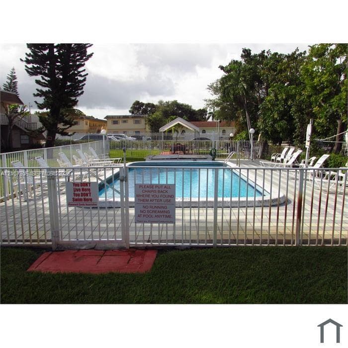 In-ground swimming pool featuring a concrete paver deck and metal perimeter fencing