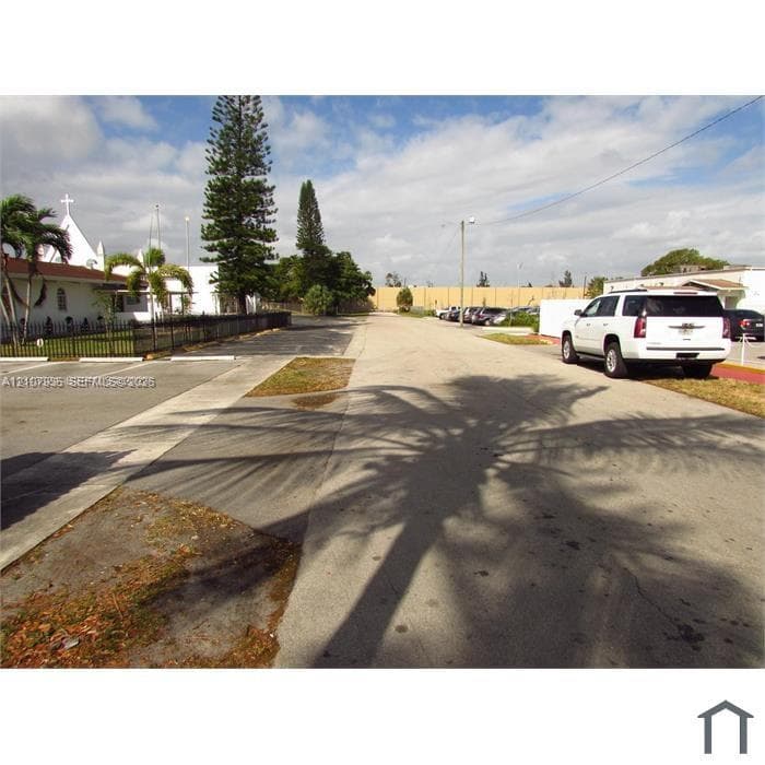 Paved parking area with concrete curbing, decorative metal fencing, and mature landscaping