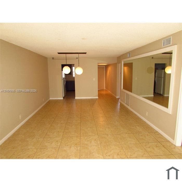 Interior space featuring tile flooring, a large wall-mounted mirror, and dual spherical pendant lighting