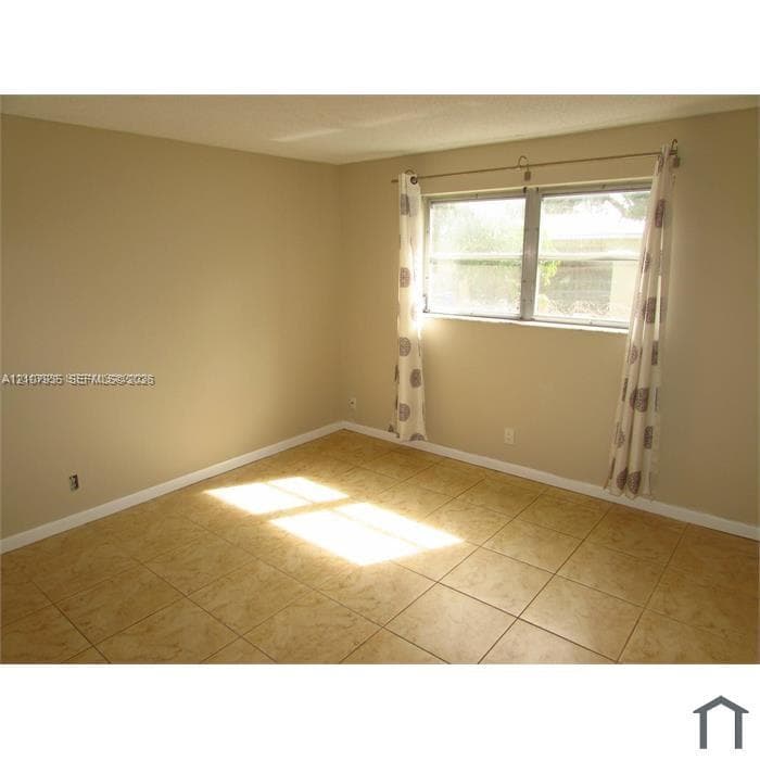 Neutral-toned interior room featuring large-format ceramic tile flooring, a horizontal sliding window, and a metal curtain rod fixture
