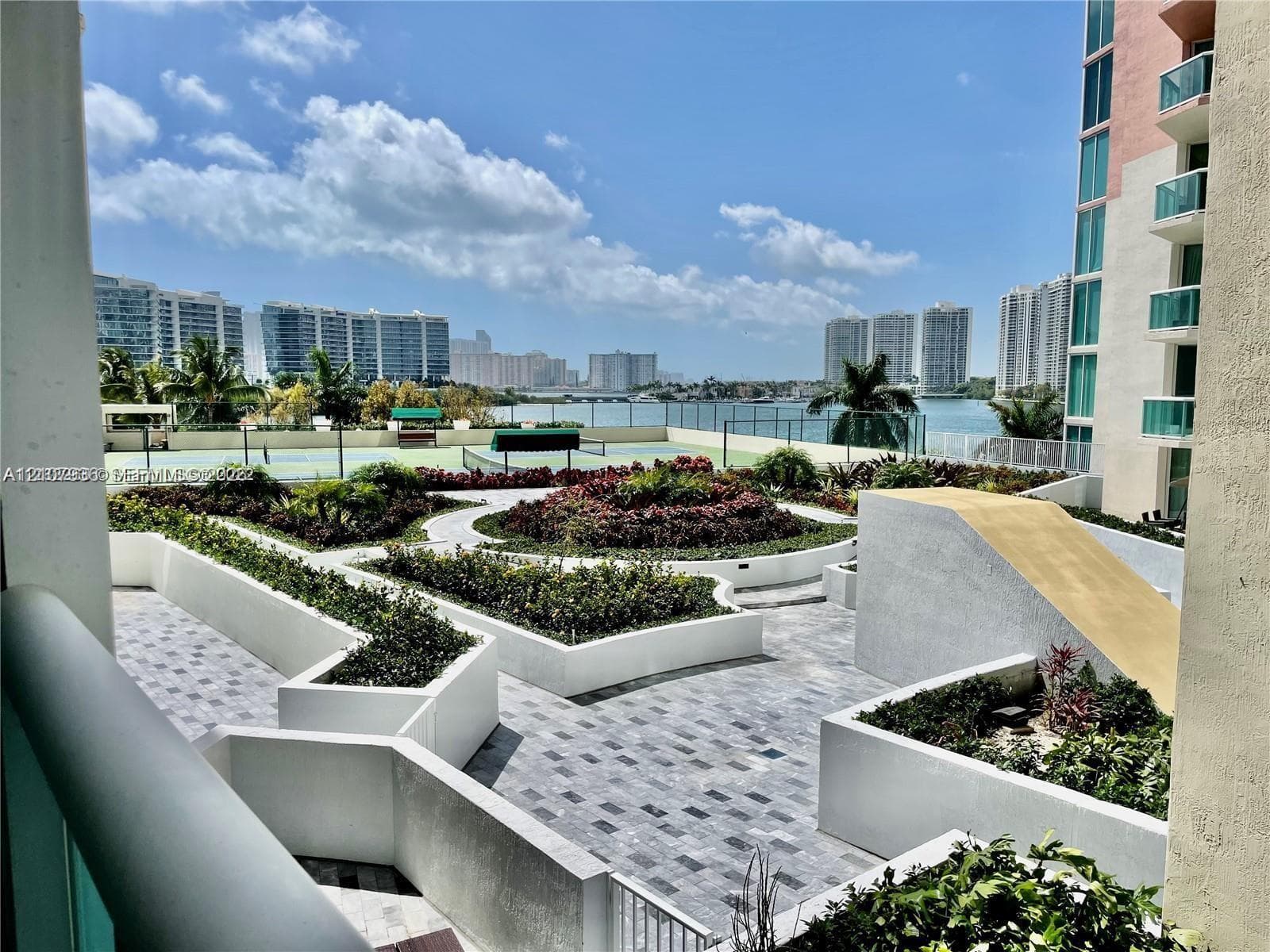 Terrace featuring paver flooring, multi-level concrete planters, and a recreational court, set against a waterfront and cityscape backdrop