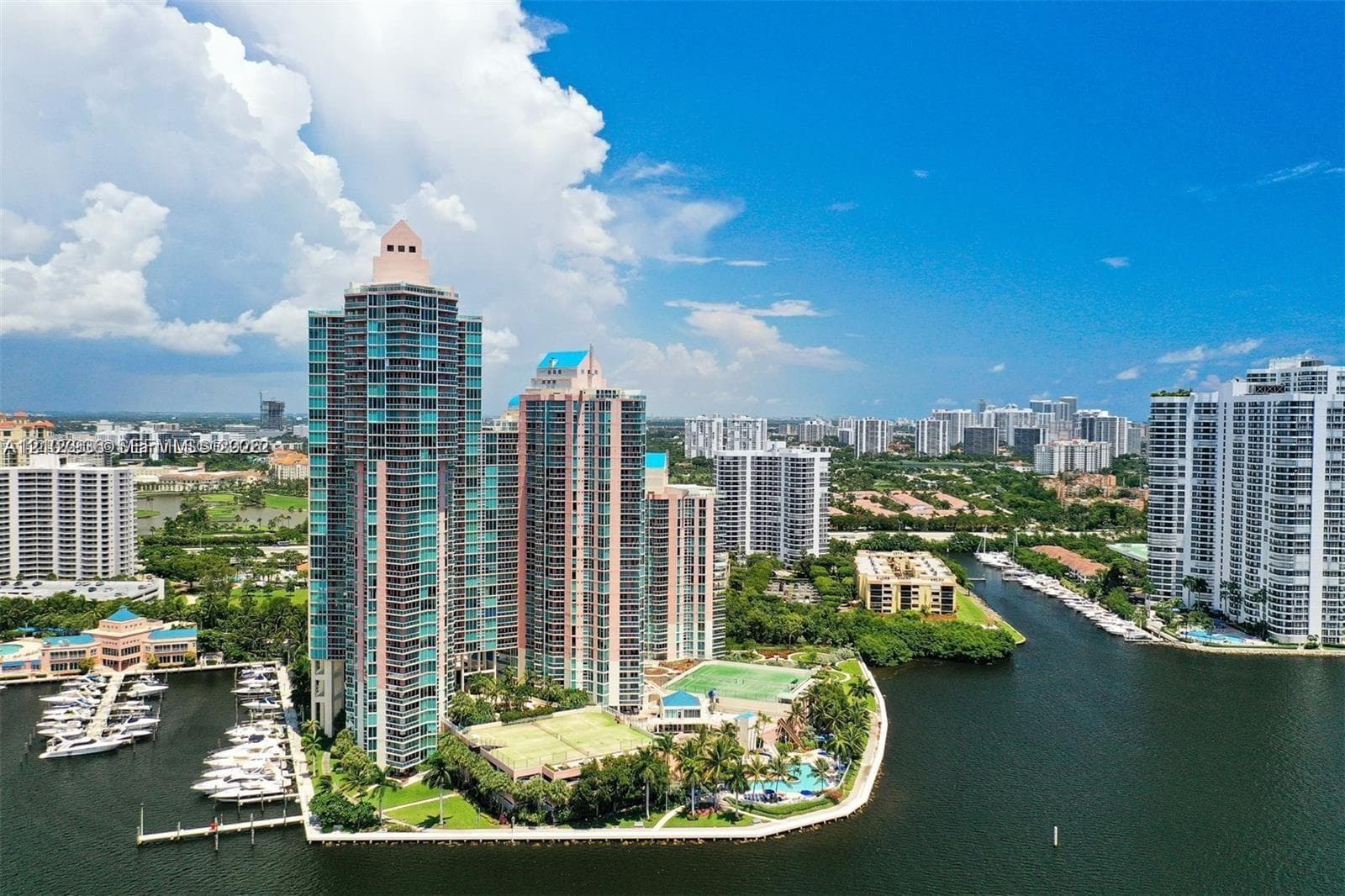 High-rise residential towers featuring private marina slips, tennis courts, and landscaped grounds situated on a waterfront peninsula