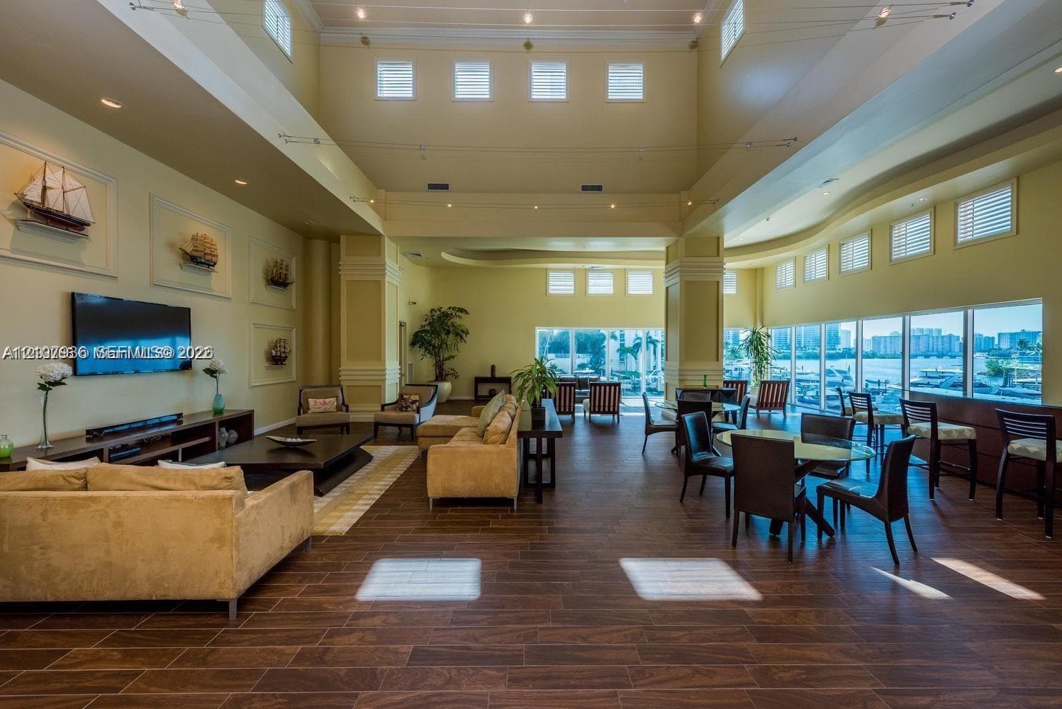 Expansive common area featuring soaring ceilings, wood-finish flooring, numerous clerestory windows, and floor-to-ceiling glass paneling
