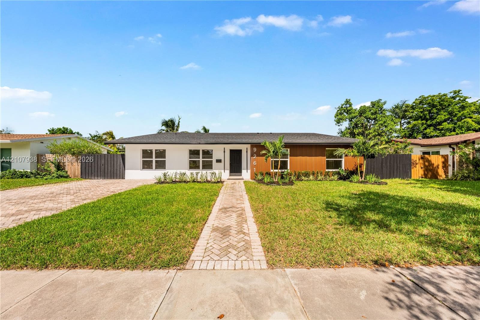 Mid-century inspired exterior featuring a crisp white and wood-panel facade, clean horizontal roofline, brick-paved walkway, and manicured front lawn