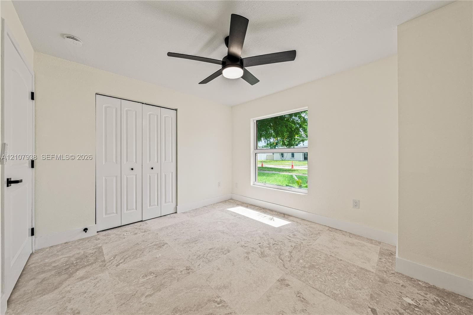 Interior space featuring stone-style flooring, a multi-panel closet with matte black hardware, and a ceiling fan with integrated lighting