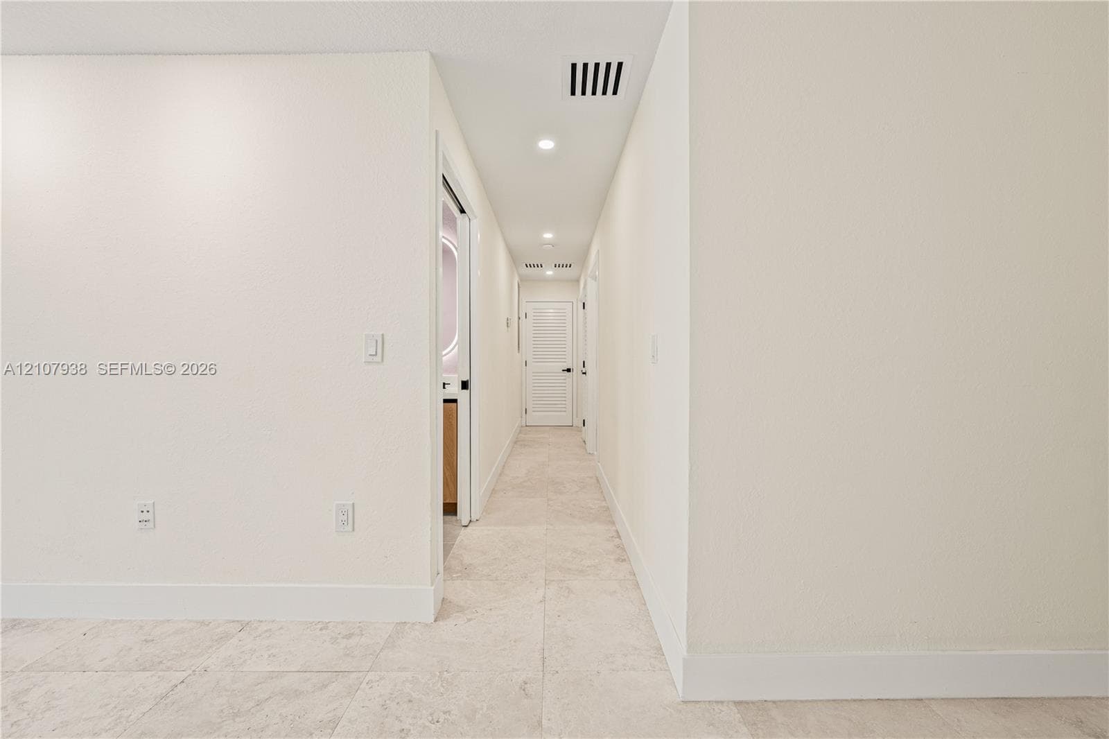 Interior hallway featuring neutral-toned tile flooring, recessed LED lighting, and white interior doors with contemporary hardware