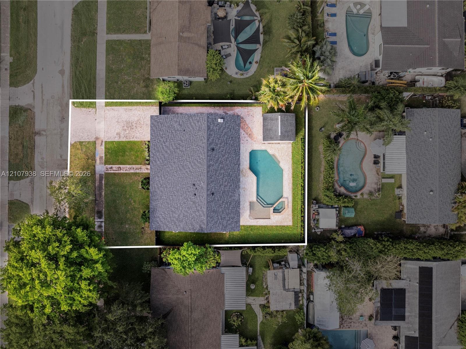 Aerial perspective of a property featuring an in-ground swimming pool, paved patio, detached storage structure, and fenced perimeter