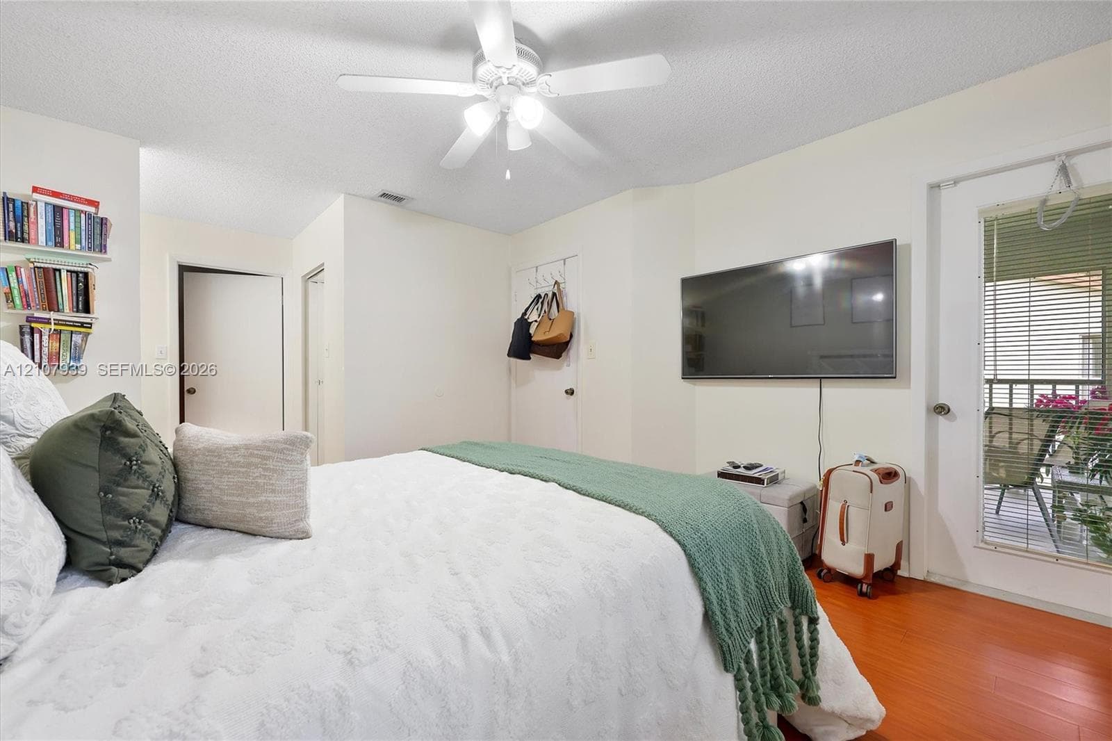 Wood-finish flooring, ceiling fan with integrated lighting, and glass-paneled door with exterior access
