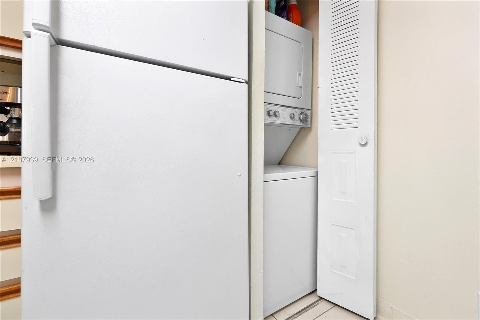 Built-in stacked laundry unit with louvered bi-fold door and full-size refrigerator