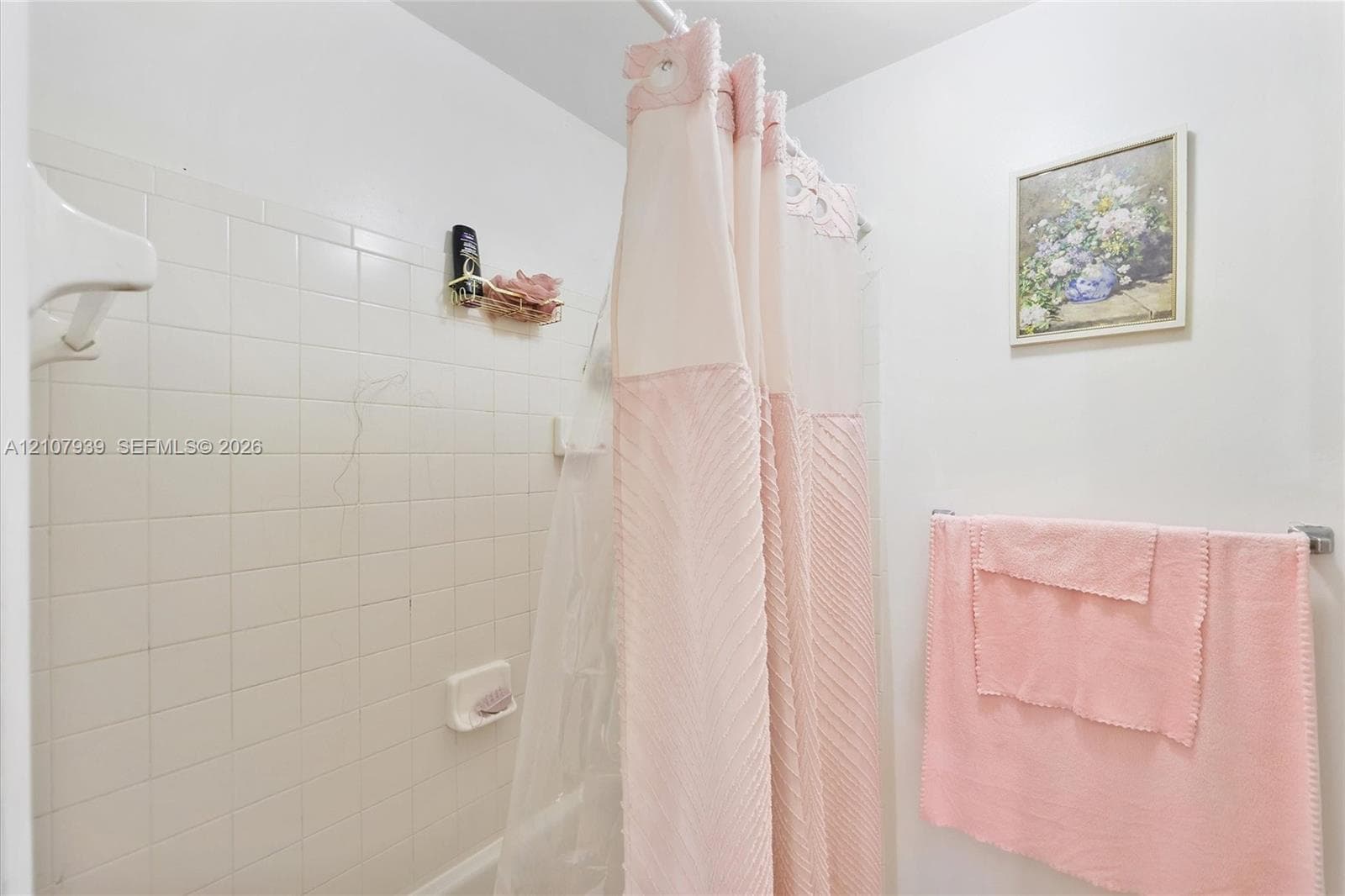 Tub enclosure featuring white ceramic wall tile and a recessed soap dish