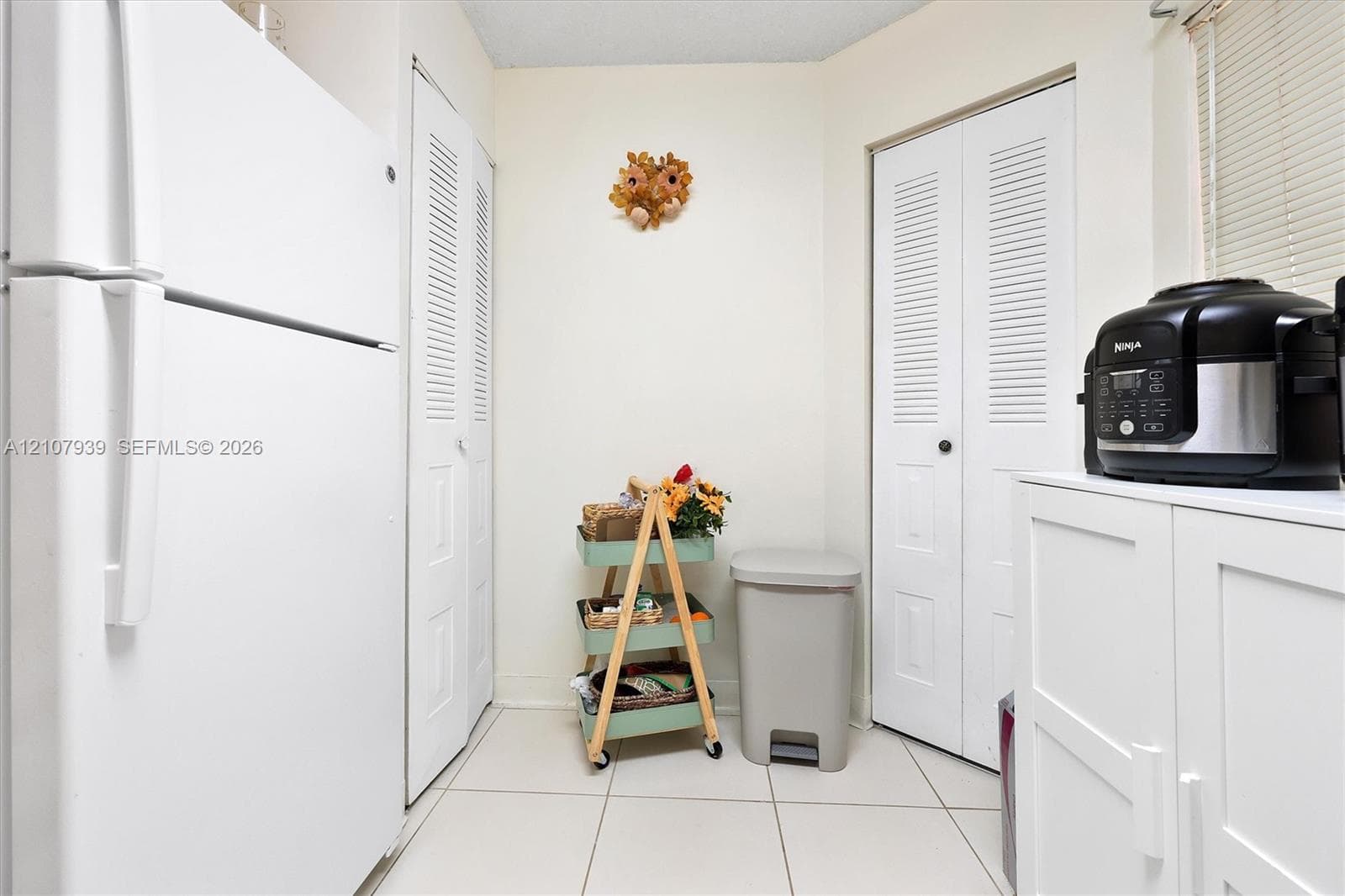 Tile flooring, two sets of white louvered-panel closets, and white cabinetry