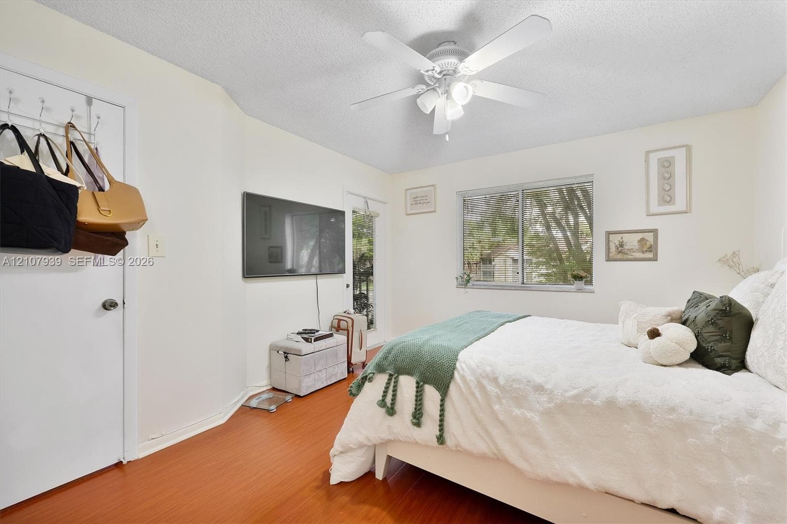 Wood-finish flooring, ceiling fan with integrated light fixture, and large sliding window