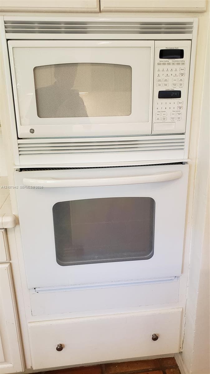 Built-in white microwave and oven unit featuring a digital control panel, integrated ventilation, and lower storage drawer