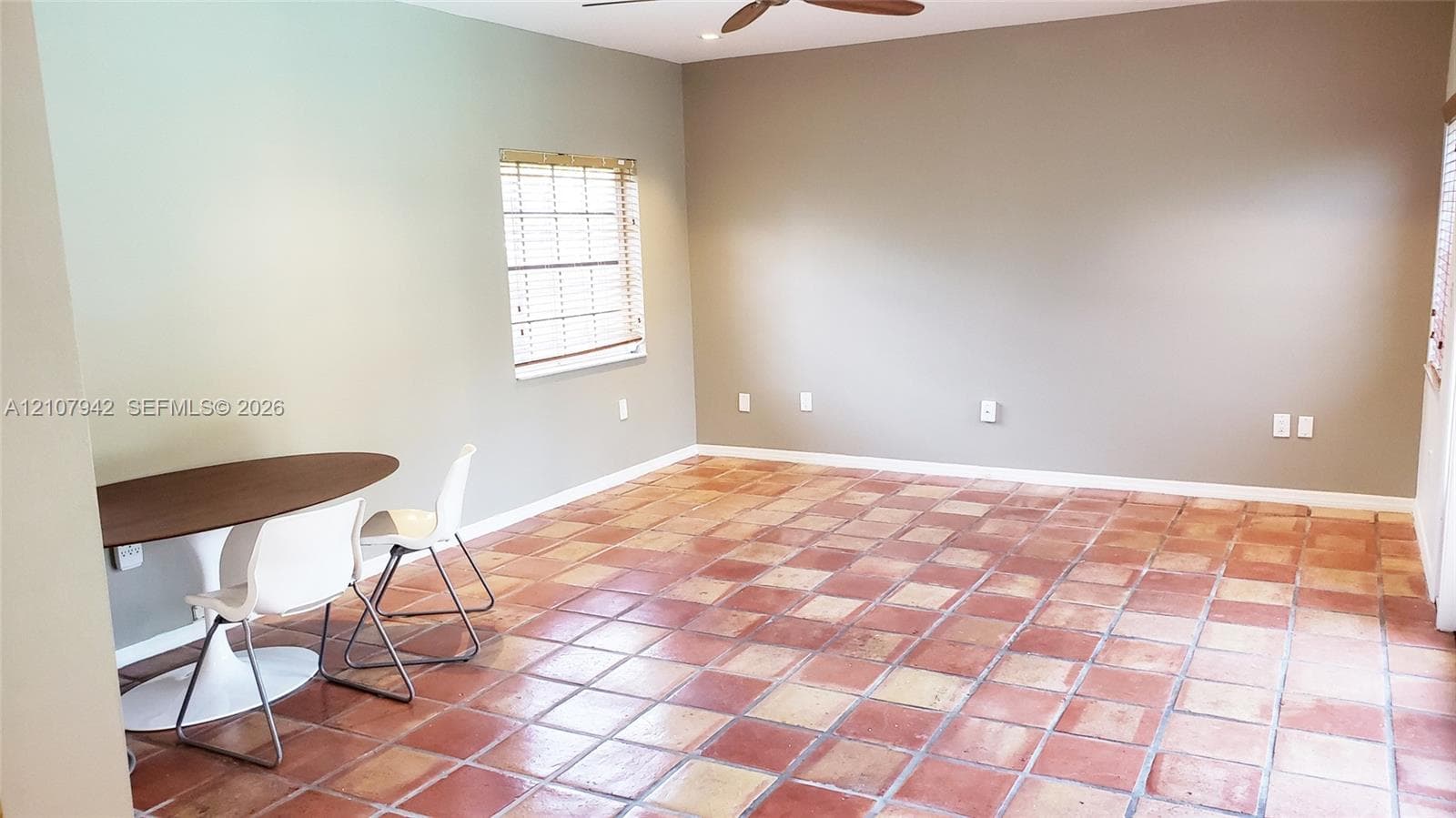Interior space featuring terracotta tile flooring, neutral wall paint, a ceiling fan, and window blinds