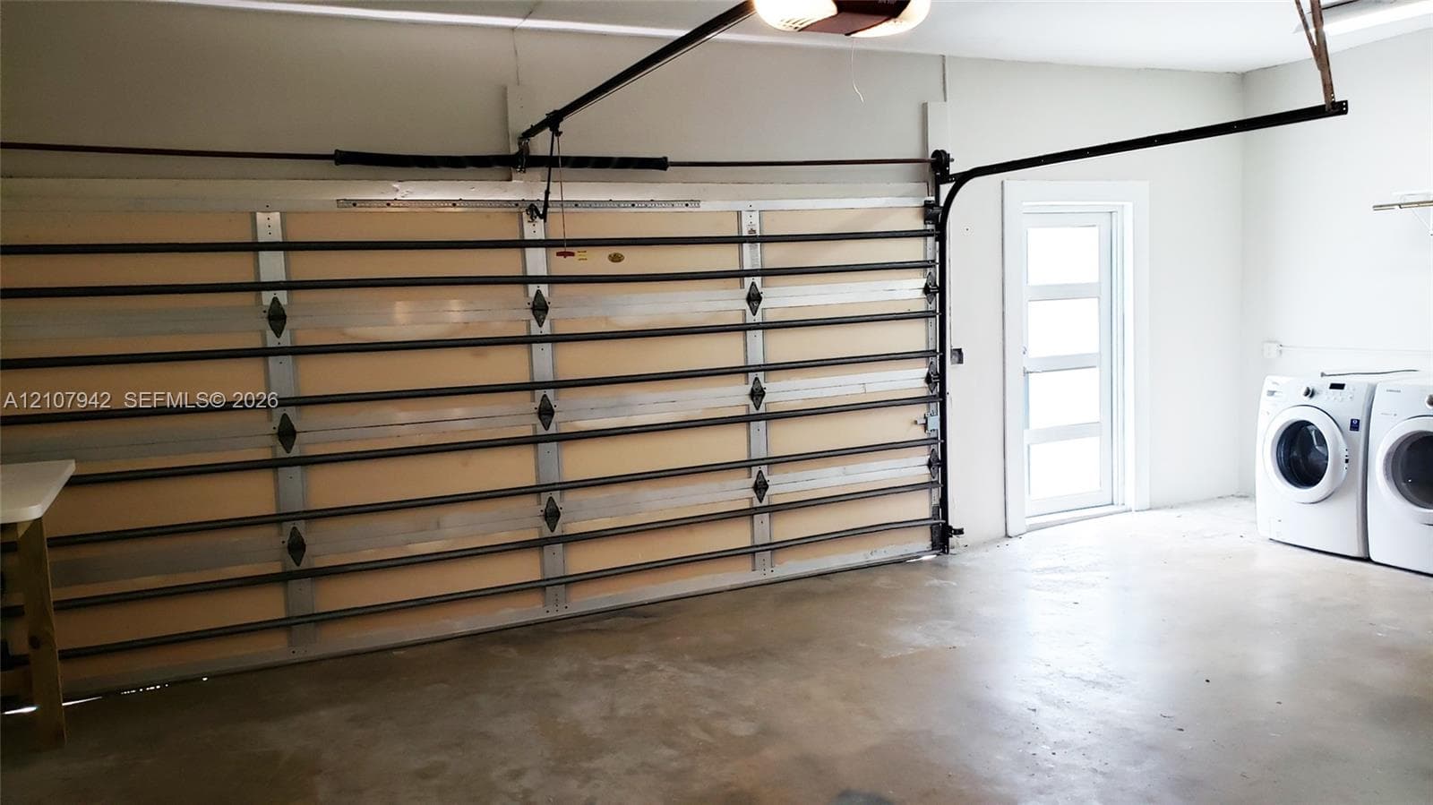 Garage featuring a multi-panel door, concrete flooring, and a dedicated laundry area with side-by-side washer and dryer