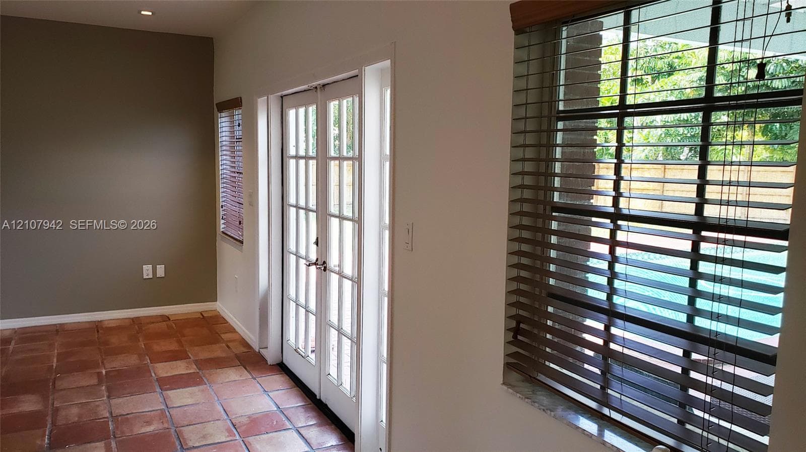 Terracotta tile flooring, double French doors, large multi-pane windows, and recessed ceiling lighting