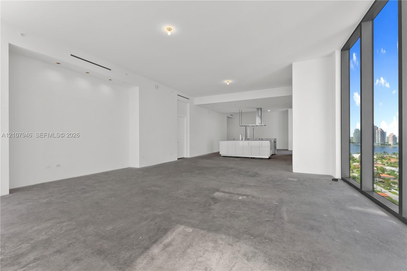 Open-concept interior featuring floor-to-ceiling windows, concrete flooring, recessed lighting, and a white kitchen island with a stainless steel range hood