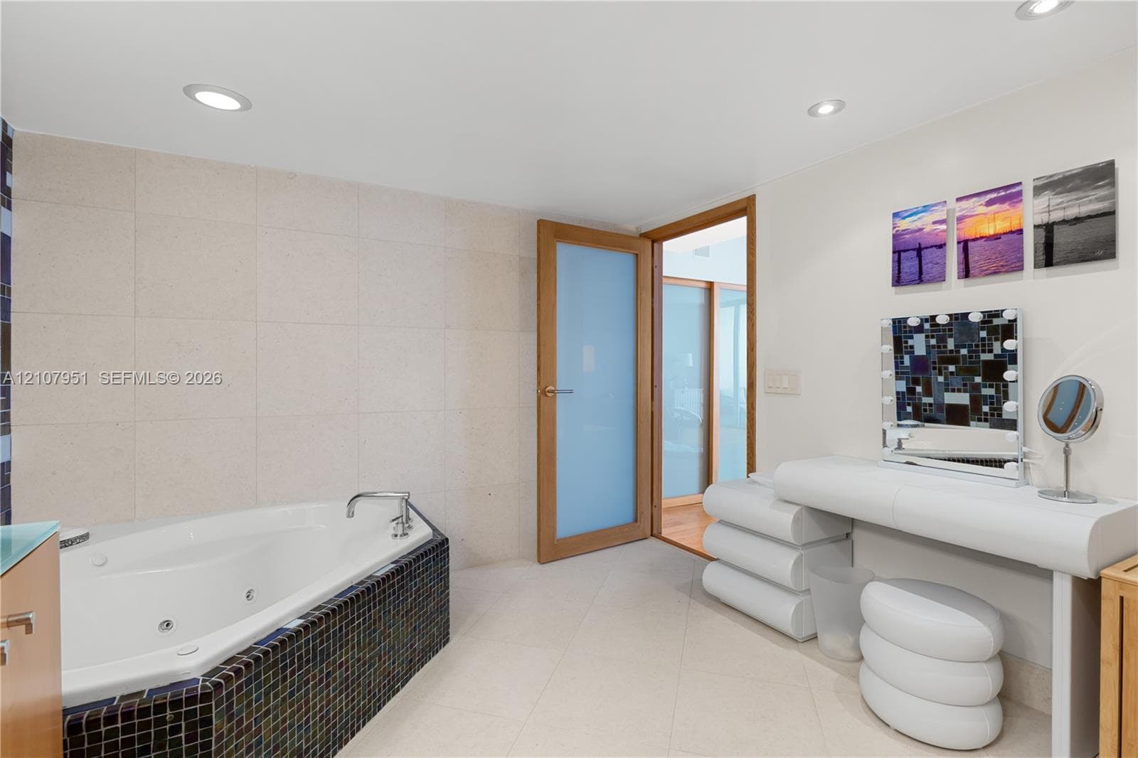 Jetted soaking tub with tile surround, recessed lighting, and a frosted-glass interior door