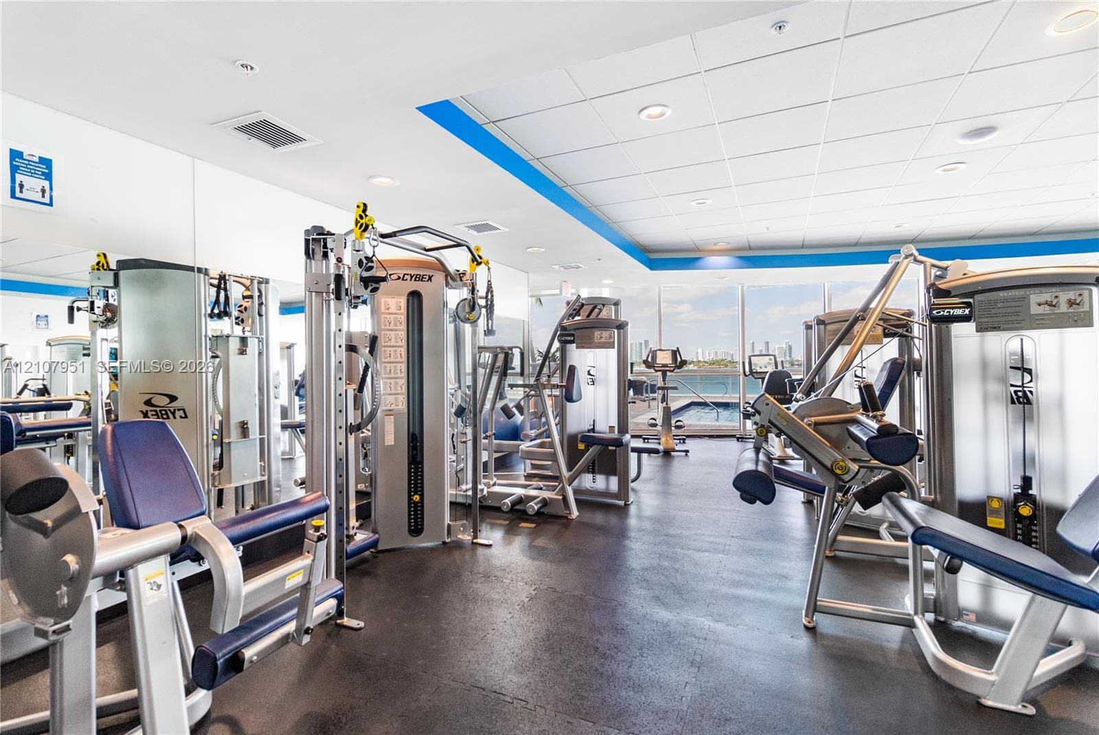 Fitness center featuring mirrored walls, resilient flooring, recessed lighting, and expansive windows with exterior water and skyline scenery