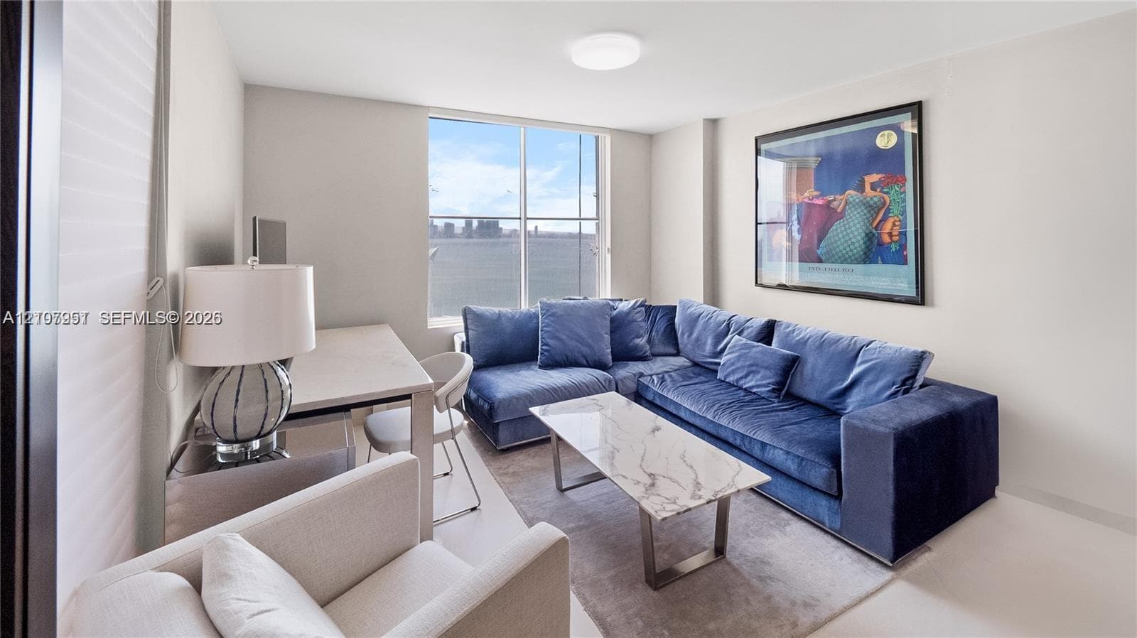 Floor-to-ceiling windows featuring expansive water and city skyline outlooks, finished with neutral wall tones and a central flush-mount ceiling light