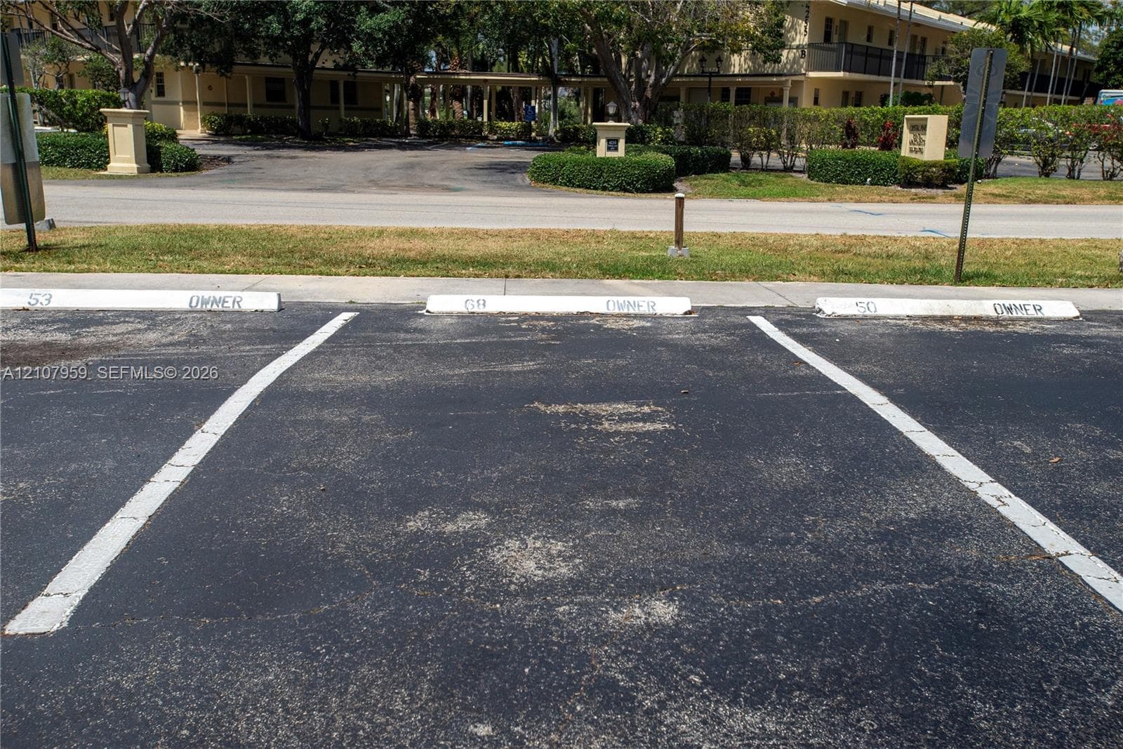 Asphalt parking area with three designated surface parking spaces and painted wheel stops