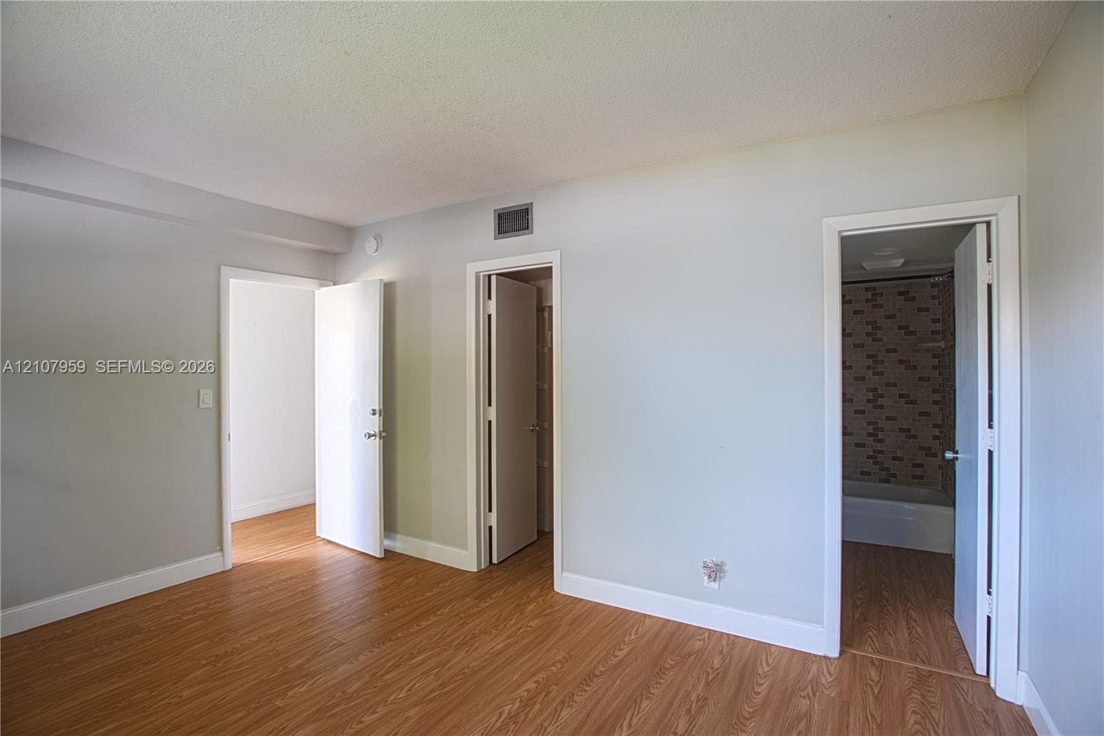 Wood-finish flooring, neutral wall tones, and doorways featuring interior slab doors