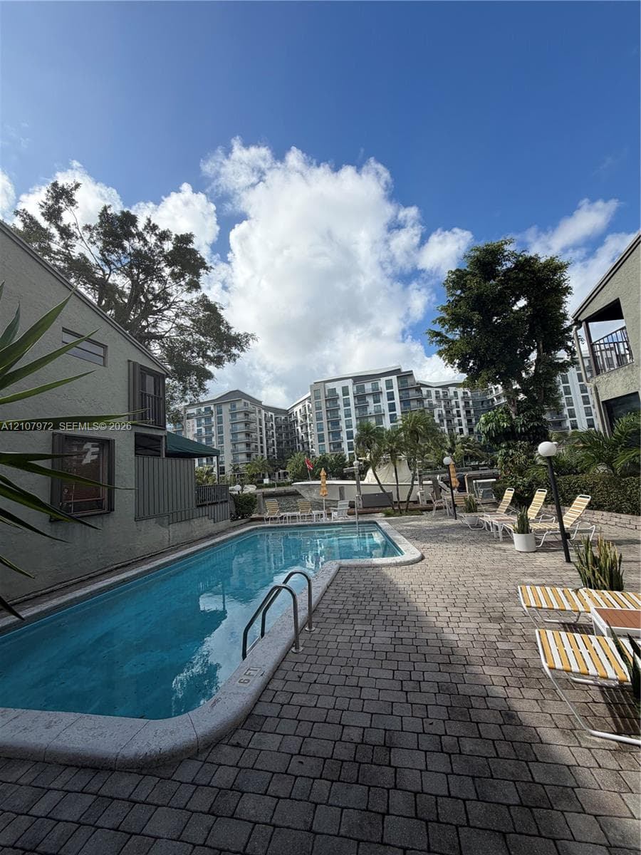 Swimming pool with integrated metal handrails and a surrounding paver stone deck