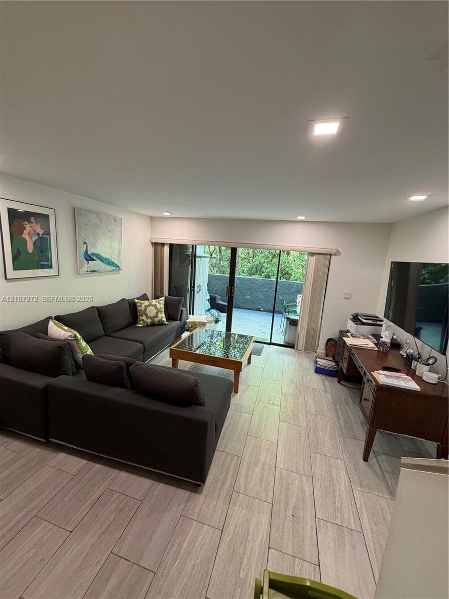 Living space featuring wood-finish tile flooring, recessed lighting, and sliding glass doors with outdoor access
