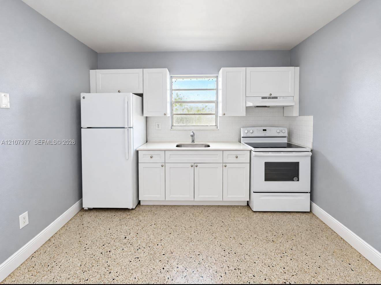 Kitchen featuring white cabinetry, solid-surface countertops, subway tile backsplash, white appliances, and terrazzo flooring