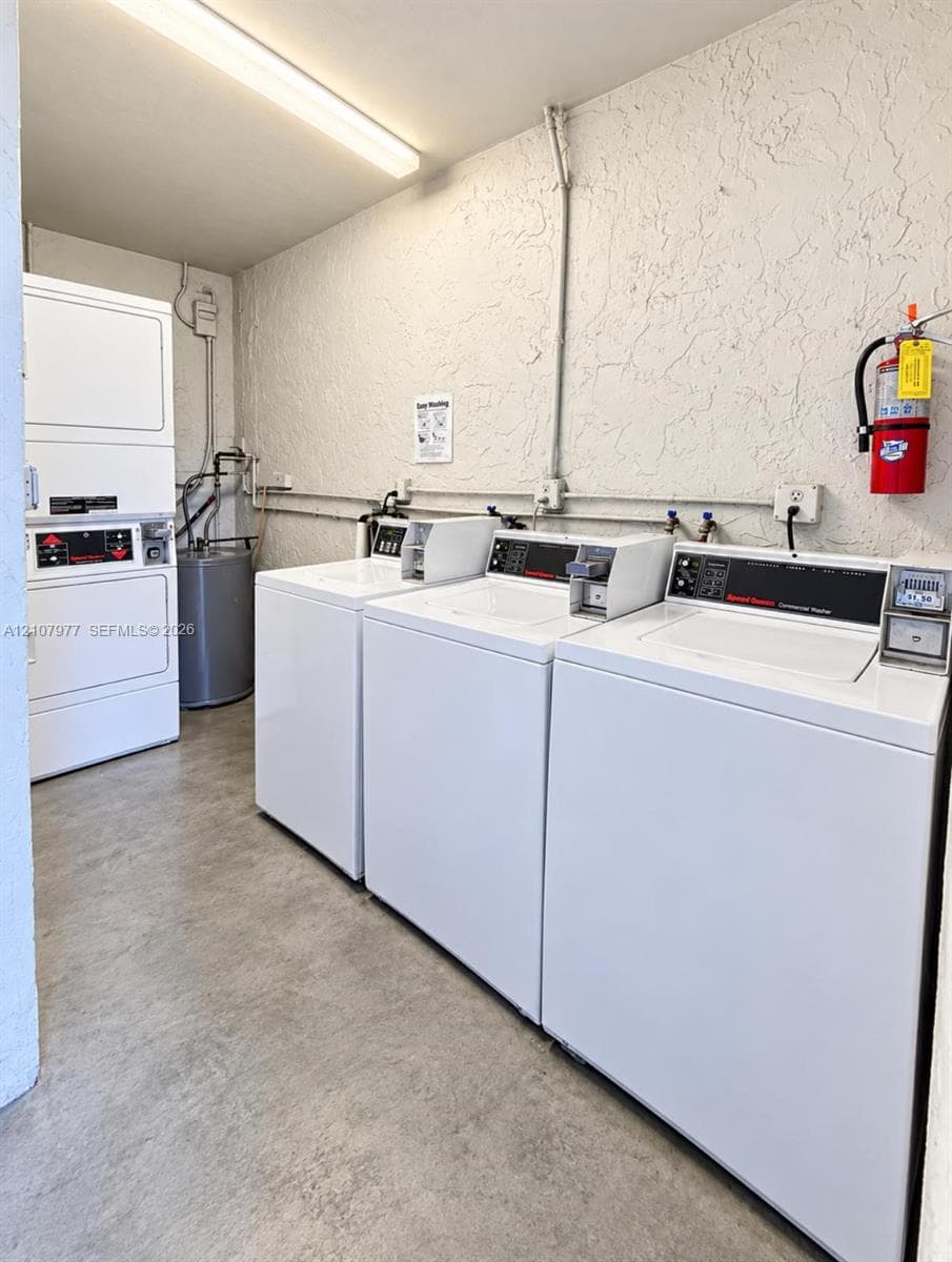 Utility room featuring multiple commercial-grade top-load washers, a stacked washer and dryer unit, and concrete flooring