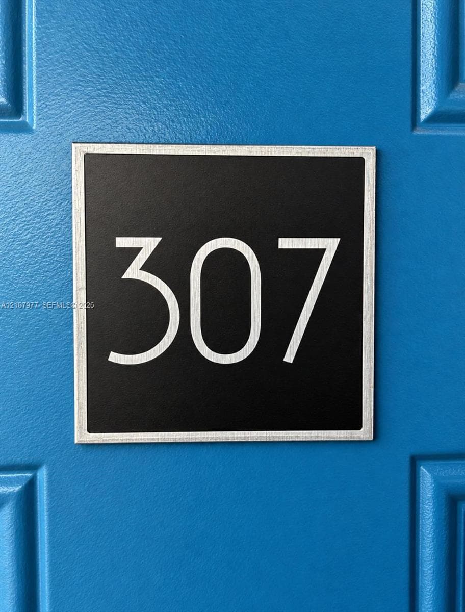 Square metallic unit signage featuring crisp white lettering mounted on a blue paneled door