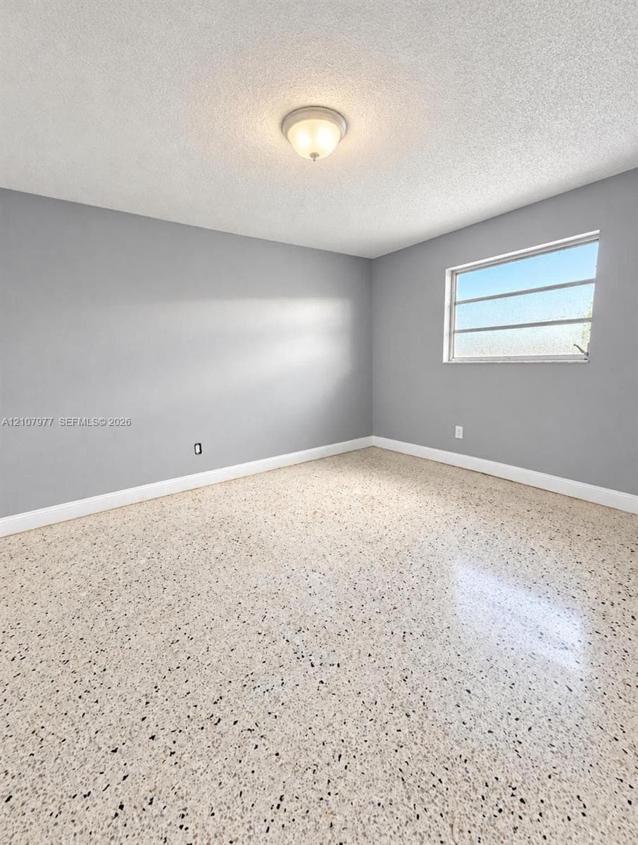 Interior room featuring polished terrazzo flooring, neutral grey wall paint, and a central flush-mount dome light fixture