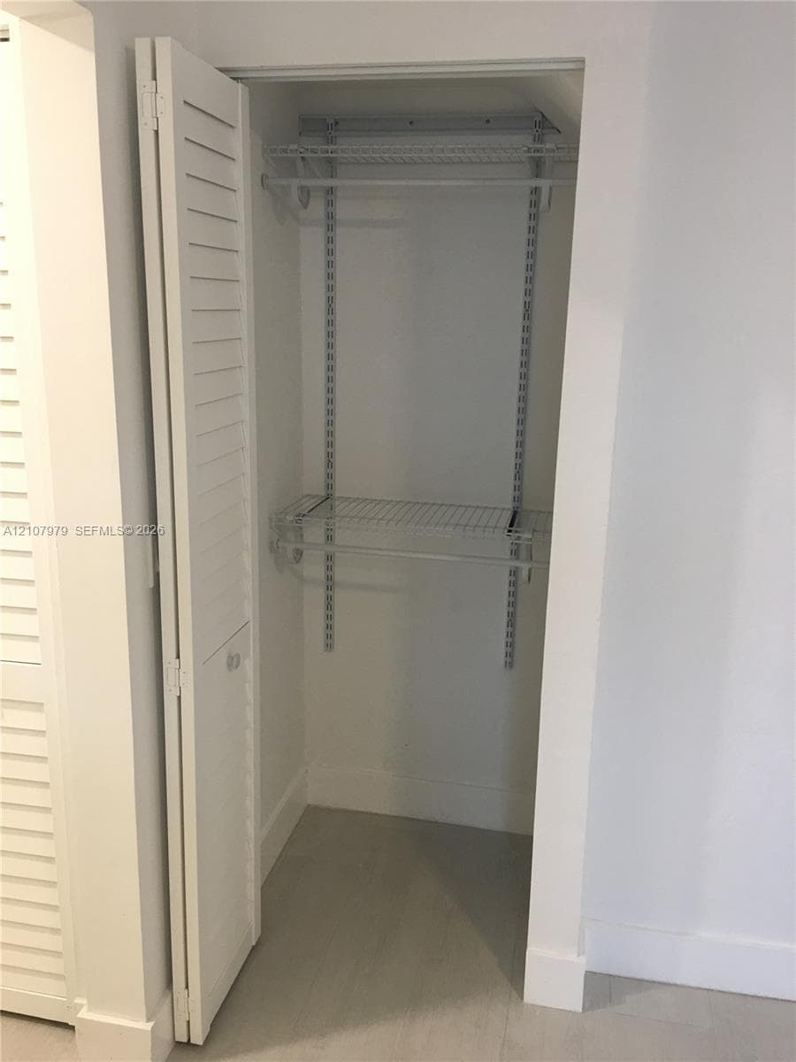 Closet featuring white louvered bi-fold doors and integrated wire shelving with adjustable wall-mounted tracks