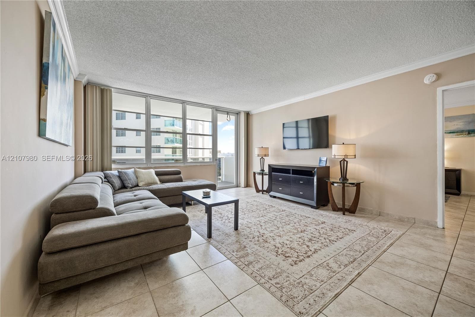 Living area featuring tile flooring, crown molding, and floor-to-ceiling windows with integrated sliding glass door