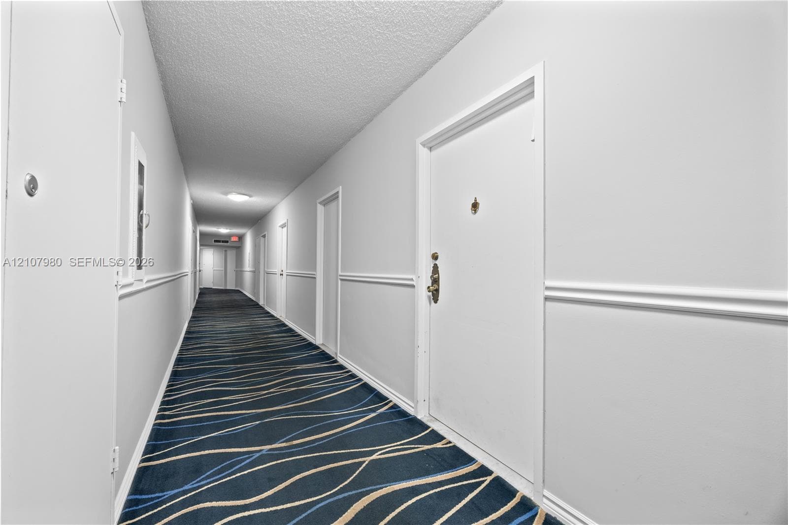 Interior hallway featuring patterned carpeting, white interior doors, and chair rail molding