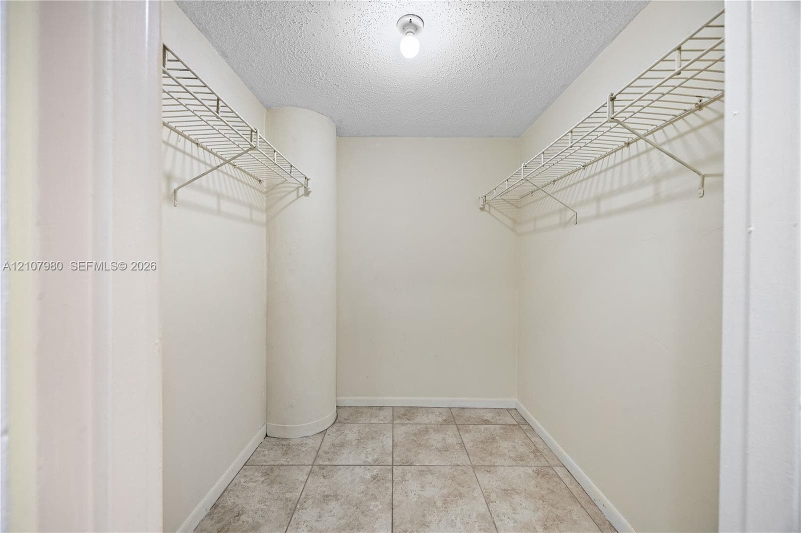 Storage area featuring tile flooring, dual-level wire shelving, and a singular ceiling-mounted light fixture