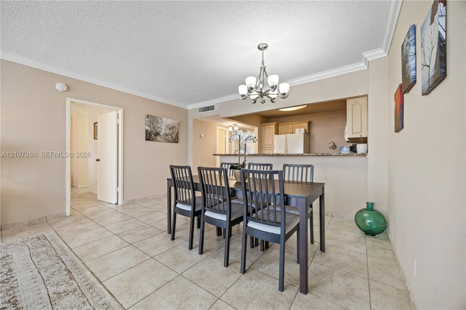 Dining area featuring neutral wall paint, tile flooring, crown molding, and an overhead multi-light chandelier